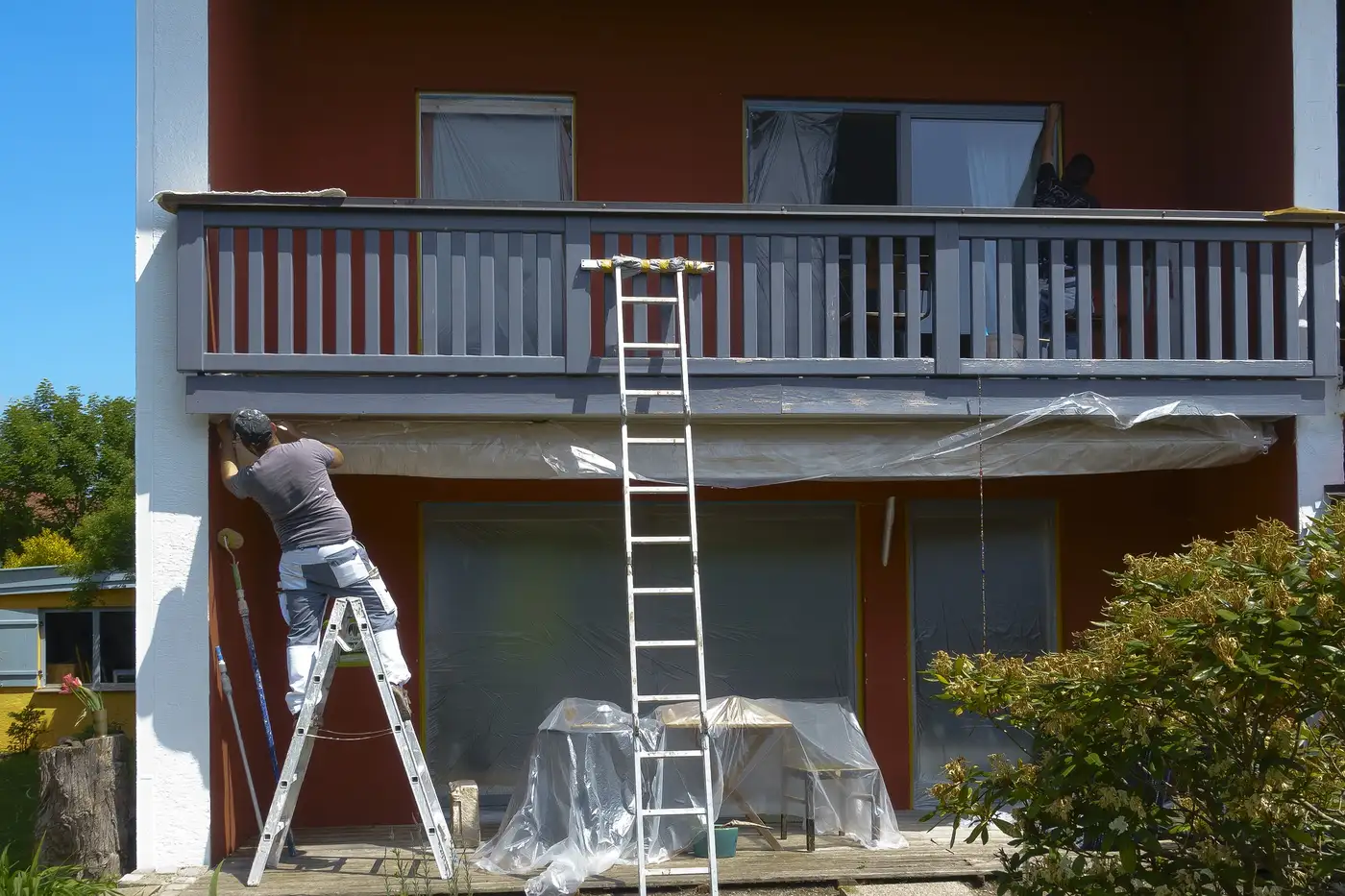 Painter on a ladder painting the exterior of a house